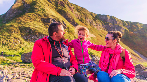 Family enjoying a giant day out at the Giant's Causeway, enjoying the breath-taking views of the coast from the world-famous stones